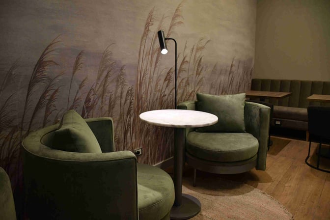 Seating area in Mendoza by AMAE Lounge features round chairs and tables with a floor lamp for individual relaxation.