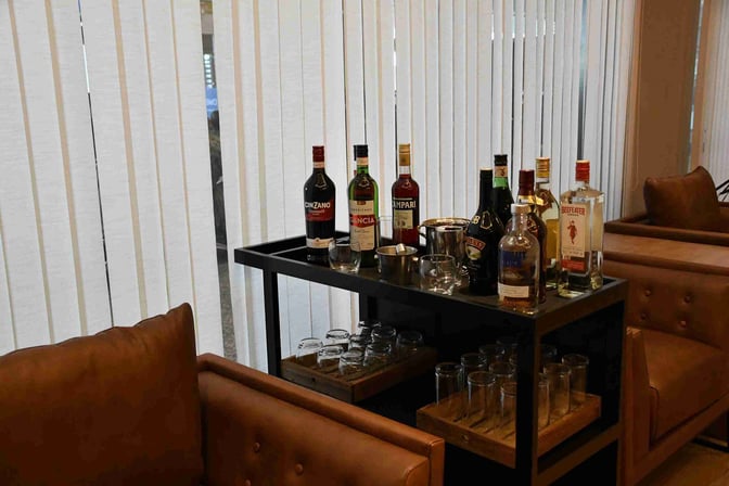 A self-serve bar area in Mendoza by AMAE Lounge at Governor Francisco Gabrielli International Airport offers various spirits and glassware.