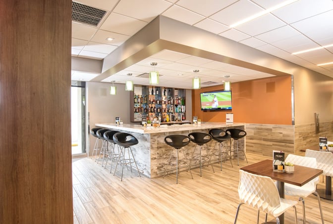 The Escape Lounge at Greenville–Spartanburg International Airport features a bar with counter seating and a television for entertainment.