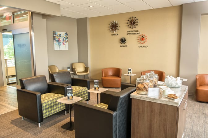 Seating area in the Escape Lounge at Greenville–Spartanburg International Airport features comfortable chairs and a snack station with cookies.