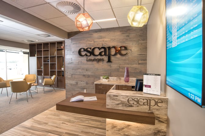The entrance to the Escape Lounge at Greenville–Spartanburg International Airport features a reception desk and seating area with airport views.