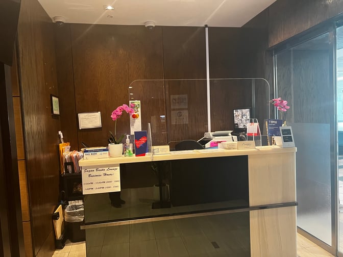 The reception desk at Sagan Bisita VIP Lounge in Guam International Airport displays business hours and offers visitor information.