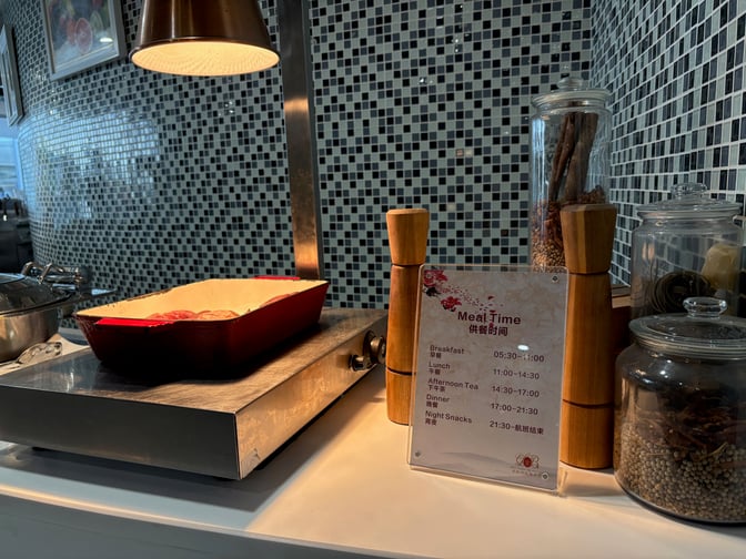 The food area in China Southern's lounge at Guangzhou Baiyun Airport features a hot dish station and a meal schedule display.