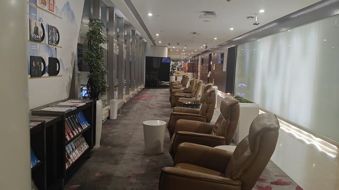 Reclining chairs in the China Southern First/Business Class Lounge at Guangzhou Baiyun Airport offer a comfortable seating area with nearby reading materials.