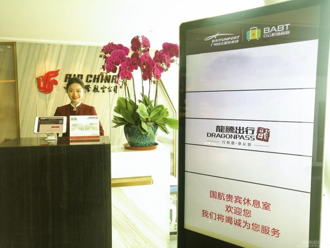 The Air China First Class Lounge entrance at Guangzhou Baiyun International Airport features a reception desk and digital information display.