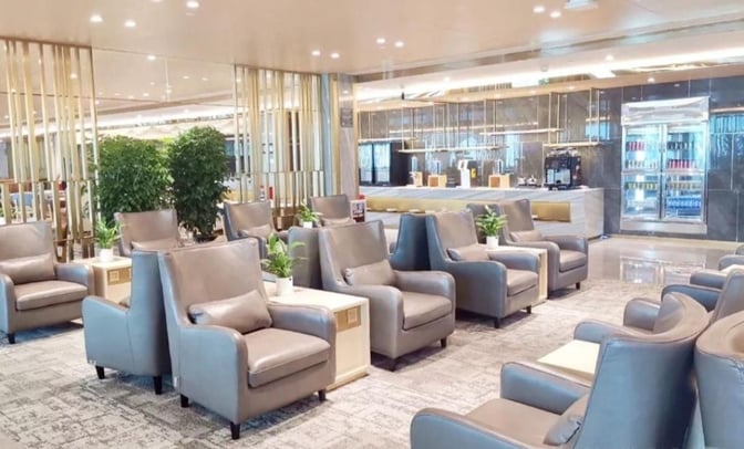 Seating in the Air China First Class Lounge at Guangzhou Airport features comfortable chairs and tables near a self-serve beverage area.