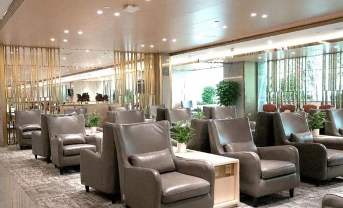 The Air China First Class Lounge at Guangzhou Baiyun International Airport features comfortable seating with individual tables and decorative plants.