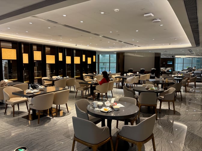 The seating area in the Premium Lounge at Guangzhou Baiyun International Airport features tables with chairs for dining and relaxation.