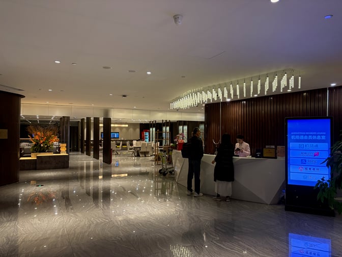 The lounge entrance at Guangzhou Baiyun International Airport features a reception desk and digital signage for airport pass members.