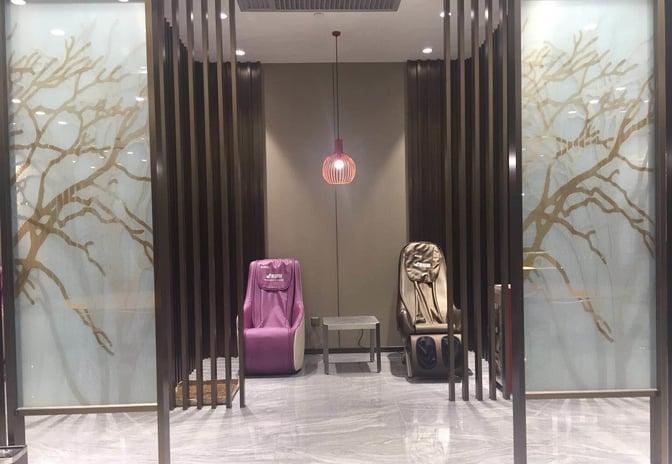 The lounge at Guangzhou Baiyun International Airport features massage chairs and a small table, providing a relaxation area for pass members.