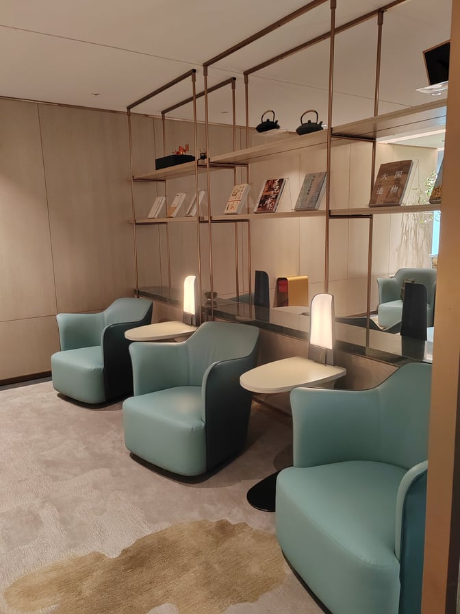Seating area in the L34 Lounge at Guangzhou Baiyun International Airport features individual chairs with side tables and decorative shelving.