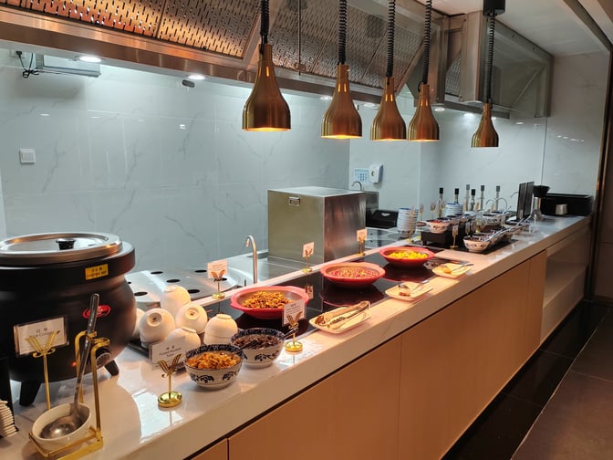 The L34 Lounge at Guangzhou Baiyun International Airport features a self-serve food station with various hot and cold dishes.