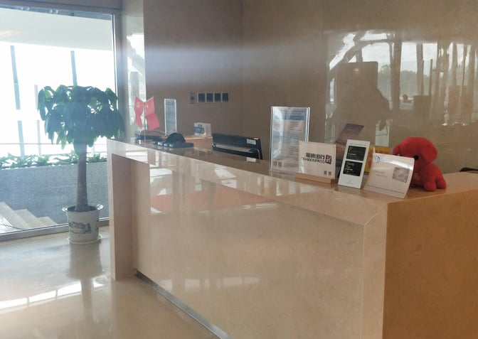 The reception desk at Guilin Liangjiang International Airport's lounge displays informational brochures and a small decorative plant.