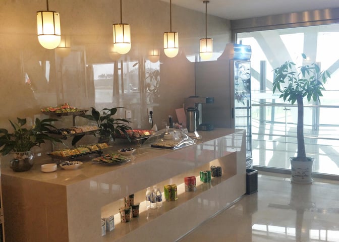 Self-serve snack station at Guilin Liangjiang International Airport lounge offers packaged snacks, beverages, and a coffee machine for travelers.