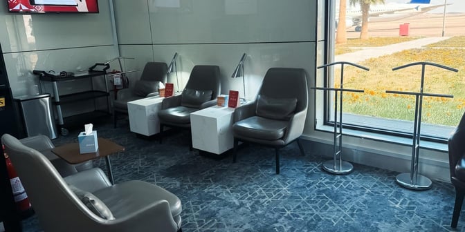 The seating area in Hayyak Lounge at Gurayat Domestic Airport features comfortable chairs, small tables, and a view of the runway.