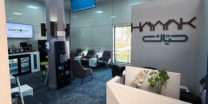 The Hayyak Lounge at Gurayat Domestic Airport features a seating area with chairs and tables, and a refreshment station with beverages.