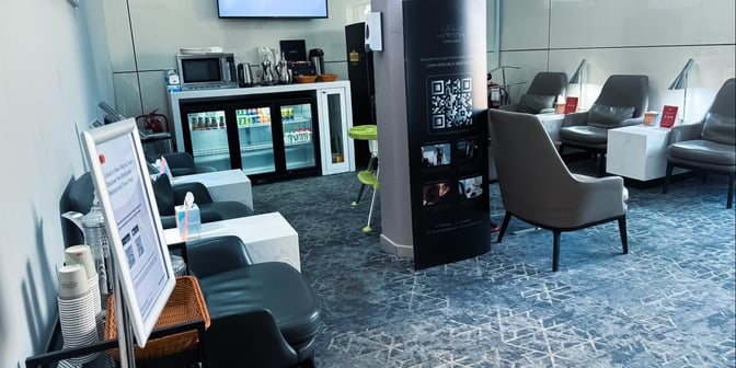 The Hayyak Lounge at Gurayat Domestic Airport features a seating area with chairs, tables, and a self-serve beverage station.