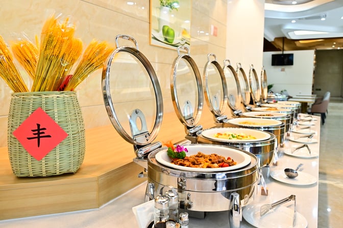 The buffet area at Easy Travel Lounge 2 in Haikou Meilan International Airport offers a variety of hot dishes in chafing dishes.