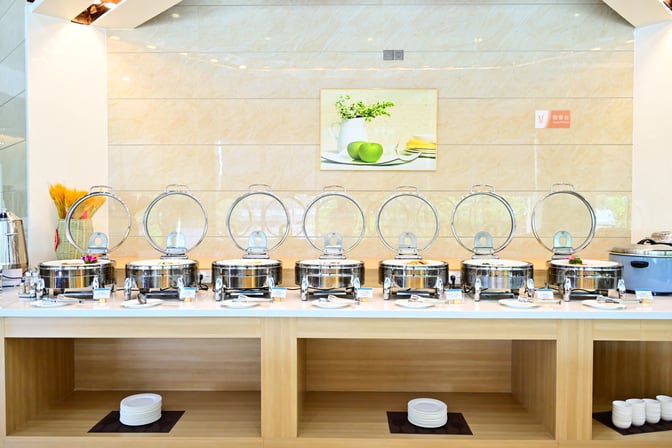 The buffet area at Easy Travel Lounge 2 in Haikou Meilan International Airport features self-serve chafing dishes with various food options.