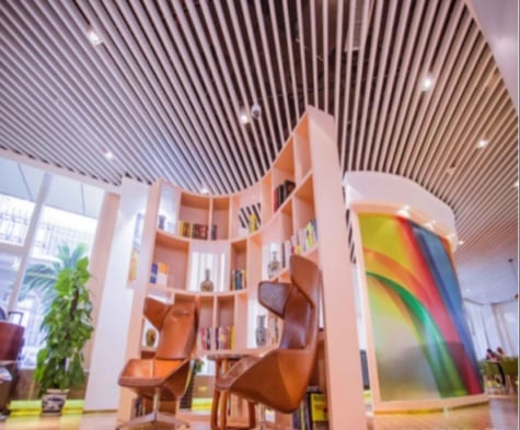 The Trvok Lounge at Haikou Meilan International Airport features a curved bookshelf with seating, offering a quiet reading area.