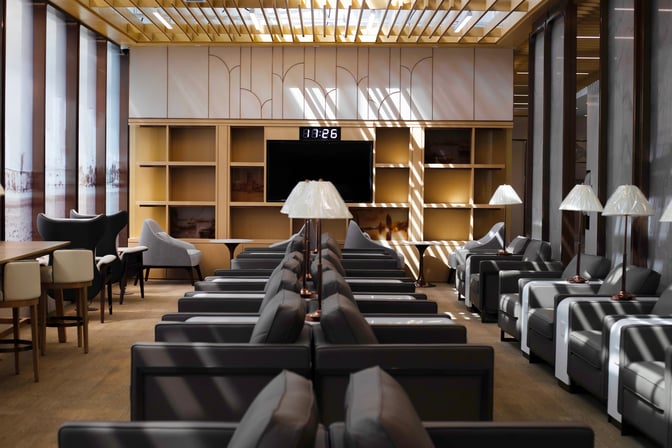 The seating area in Hainan Airlines Lounge at Haikou Meilan International Airport features rows of armchairs and a central television.