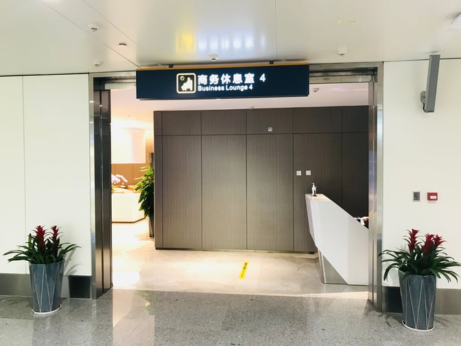 The entrance to Business Lounge 4 at Haikou Meilan International Airport features a reception desk and potted plants.