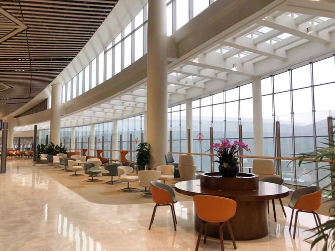The International First Class Lounge at Haikou Meilan International Airport features spacious seating areas with tables and chairs overlooking large windows.