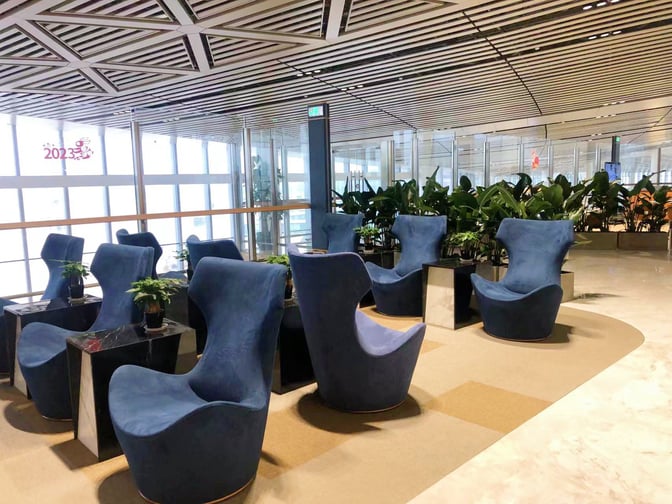 The seating area in the International First Class Lounge at Haikou Meilan International Airport features comfortable chairs and small tables with plants.