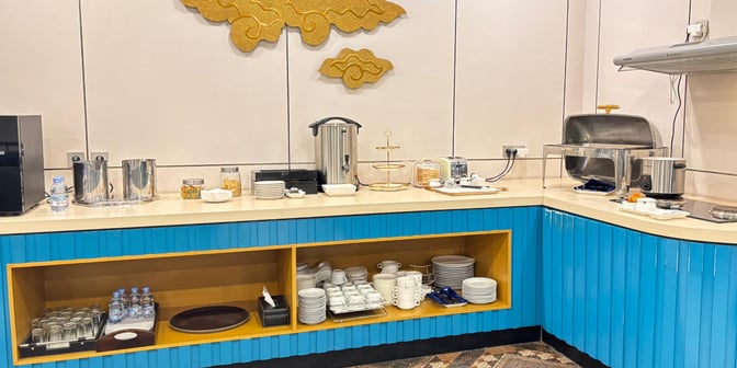 The Saphire Lounge at Halim Perdanakusuma Airport features a self-serve food station with beverages, snacks, and dining ware for guests.