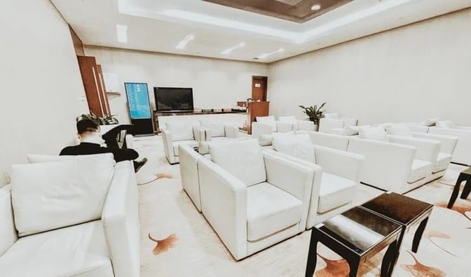 The seating area in the First Class Lounge at Hangzhou Xiaoshan International Airport features multiple armchairs and a television for relaxation.