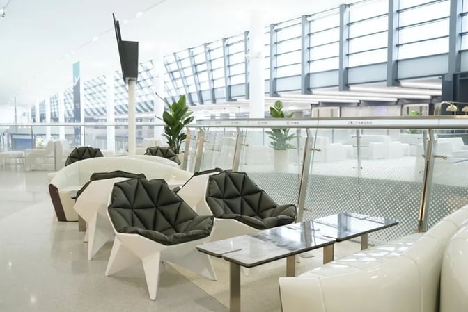 The seating area in VIP Lounge V25 at Hangzhou Xiaoshan International Airport features modern chairs and tables overlooking the terminal.