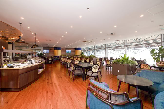 The SH Premium Lounge at Noi Bai International Airport features a spacious seating area with dining tables and a self-serve food station.