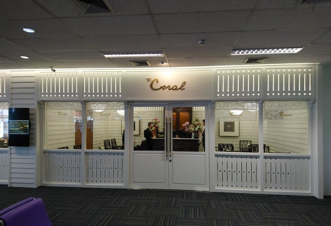 The Coral Executive Lounge entrance at Hat Yai International Airport features a reception desk and visible seating area through glass windows.