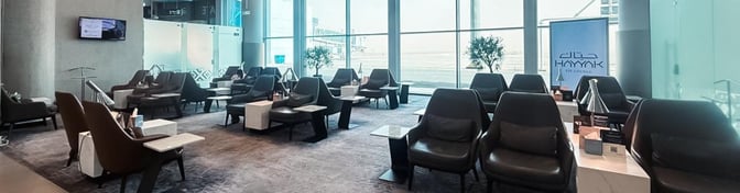 The Hayyak Lounge at Arar Domestic Airport features comfortable seating with tables, offering views of the airport through large windows.