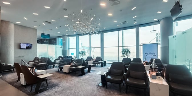The Hayyak Lounge at Arar Domestic Airport features comfortable seating with individual tables, offering views of the airport tarmac.