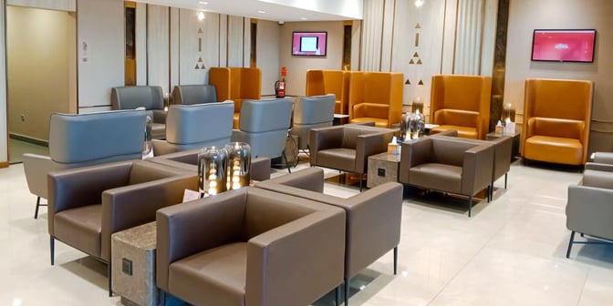 The seating area in Hayyak Lounge at Prince Naif bin Abdulaziz International Airport features armchairs and high-backed chairs with small tables.
