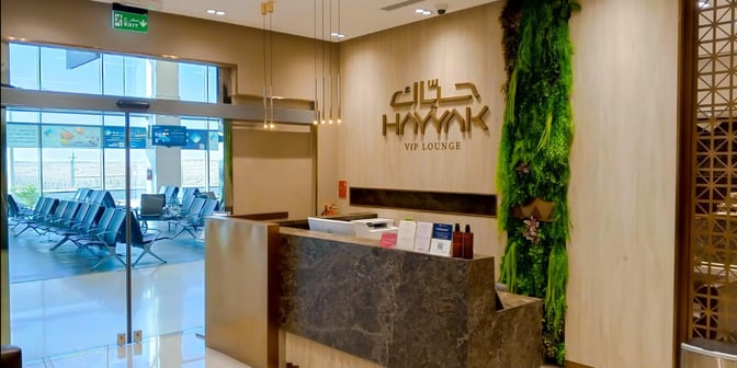 The Hayyak Lounge entrance at Prince Naif bin Abdulaziz International Airport features a reception desk and seating visible through glass doors.