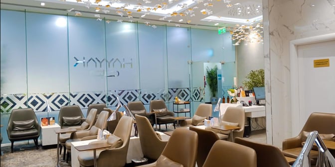 The Hayyak Lounge at Prince Naif bin Abdulaziz International Airport features comfortable seating with tables and a reception desk for guest services.