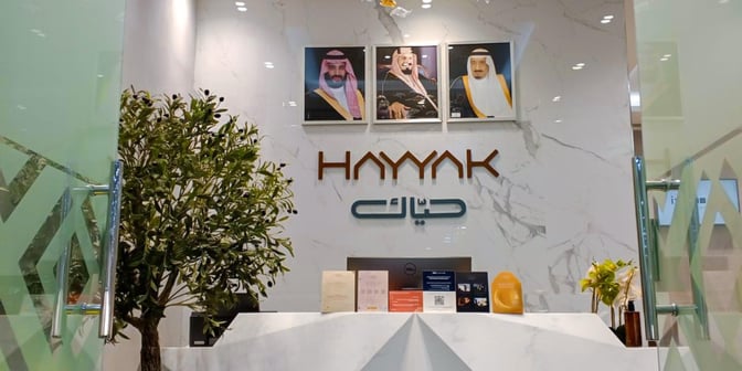 The entrance to Hayyak Lounge at Prince Naif bin Abdulaziz International Airport features a reception desk with informational brochures.
