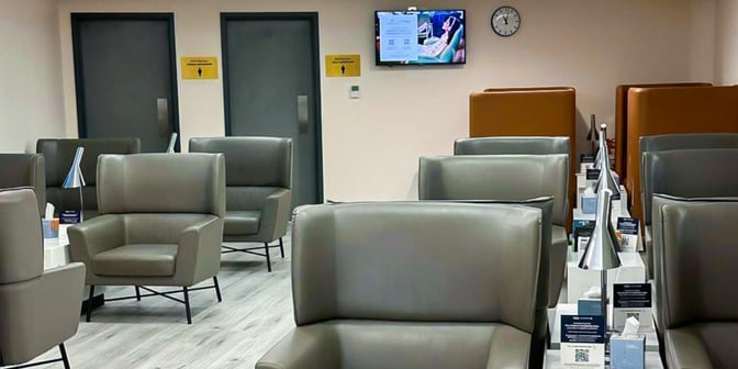 The seating area in Hayyak Lounge at Najran Regional Airport features individual armchairs with side tables and informational displays.