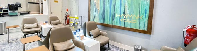 The seating area in Hayyak Lounge at Ta’if International Airport features comfortable chairs with side tables and a self-serve coffee station.