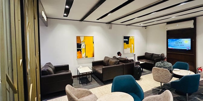 The seating area in UCB Imperial Lounge at Hazrat Shahjalal International Airport features sofas, a television, and small tables for relaxation.