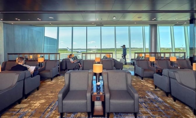 The Plaza Premium Lounge at Helsinki-Vantaa Airport features comfortable seating with views of the runway through large windows.