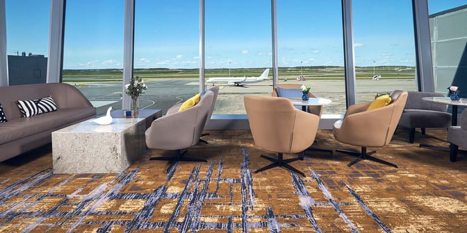 Seating area in Plaza Premium Lounge at Helsinki-Vantaa Airport offers comfortable chairs and tables with expansive views of the runway.