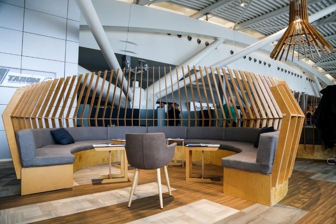 Curved booth seating in the Dacia Business Lounge at Henri Coanda International Airport offers semi-private spaces with tables for travelers.