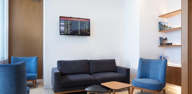 The seating area in the Goldair Handling Lounge at Heraklion International Airport features a sofa, armchairs, and a flight information screen.