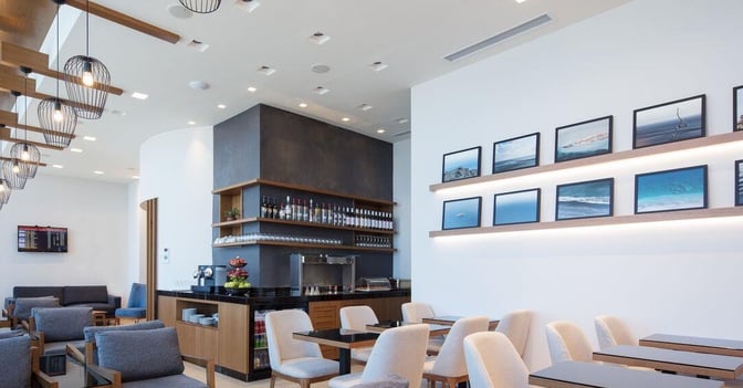 The Goldair Handling Lounge at Heraklion International Airport features a seating area with tables, chairs, and a bar offering beverages.