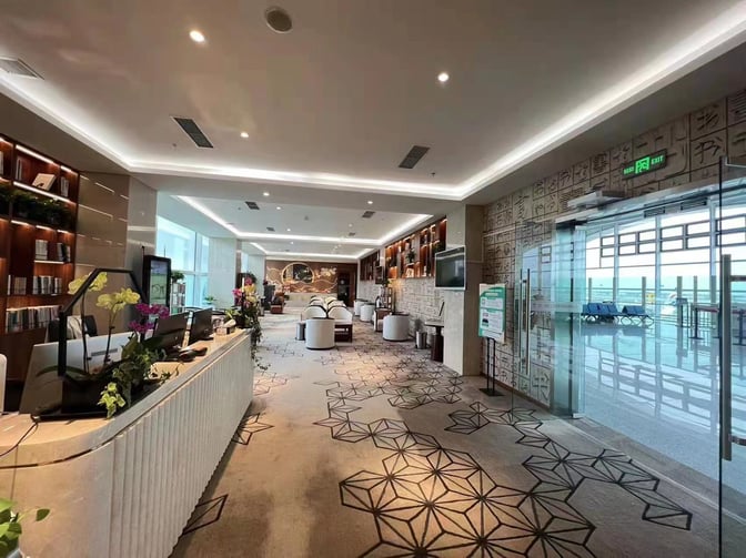 The First Class Lounge at Hohhot Baita International Airport features a reception desk and seating area with airport views.