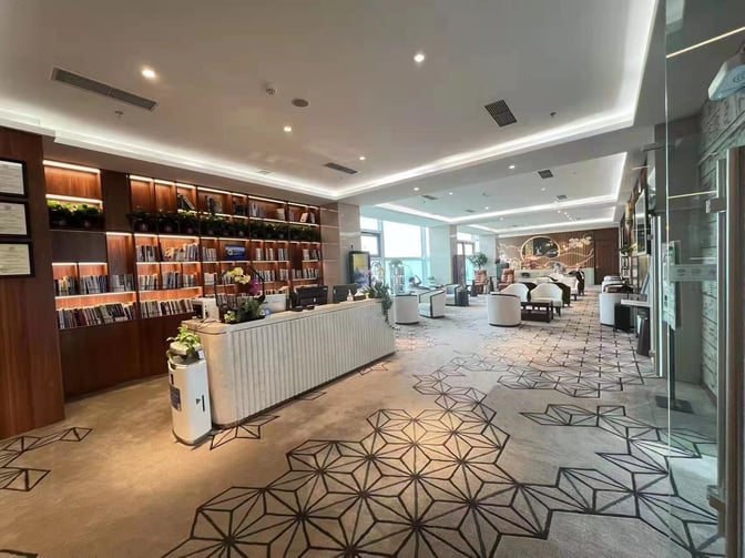 The First Class Lounge at Hohhot Baita International Airport features a reception desk, book-lined shelves, and comfortable seating areas for travelers.