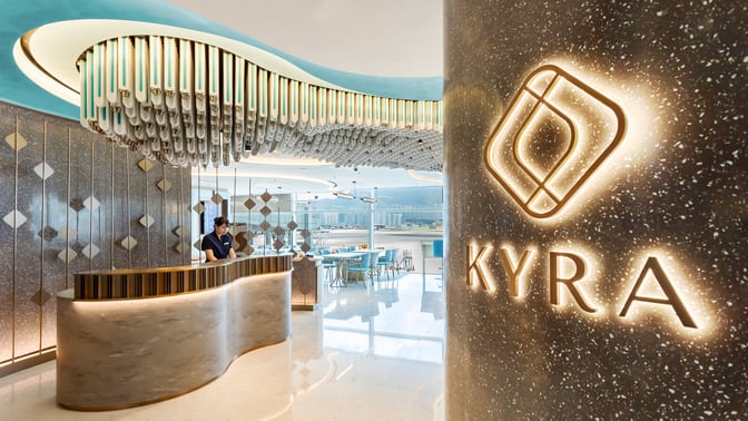 The Kyra Lounge entrance at Hong Kong International Airport features a reception desk and seating area with airport views.